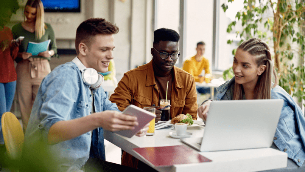 Different types of teenage friendships critical to wellbeing as we age, scientists find Horizontal Happy College Friends Using Computer While Studying In Cafeteria. .png